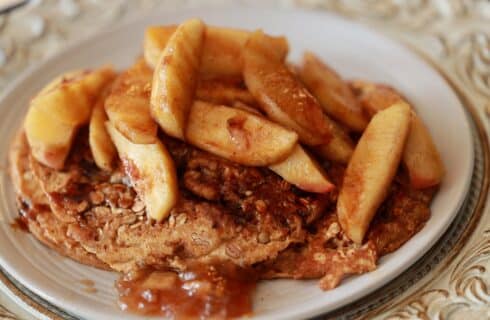 apple cinnamon granola pancakes, with fresh apples on top, drizzled with apple cinnamon syrup