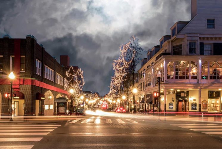 Main street surrounded by retails shops and trees all lighted up at night