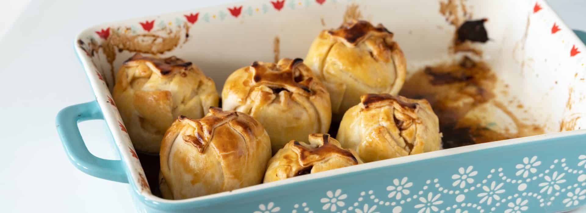 Close up view of apple dumplings in a light blue casserole dish