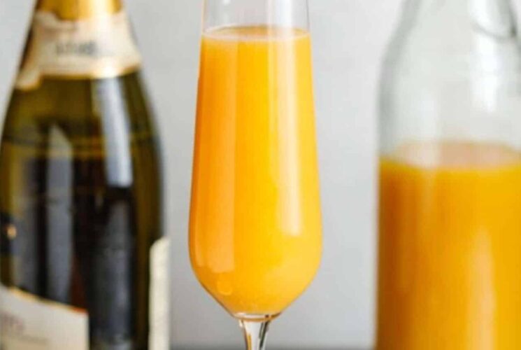 glass of mimosa with prosecco bottle and orange juice