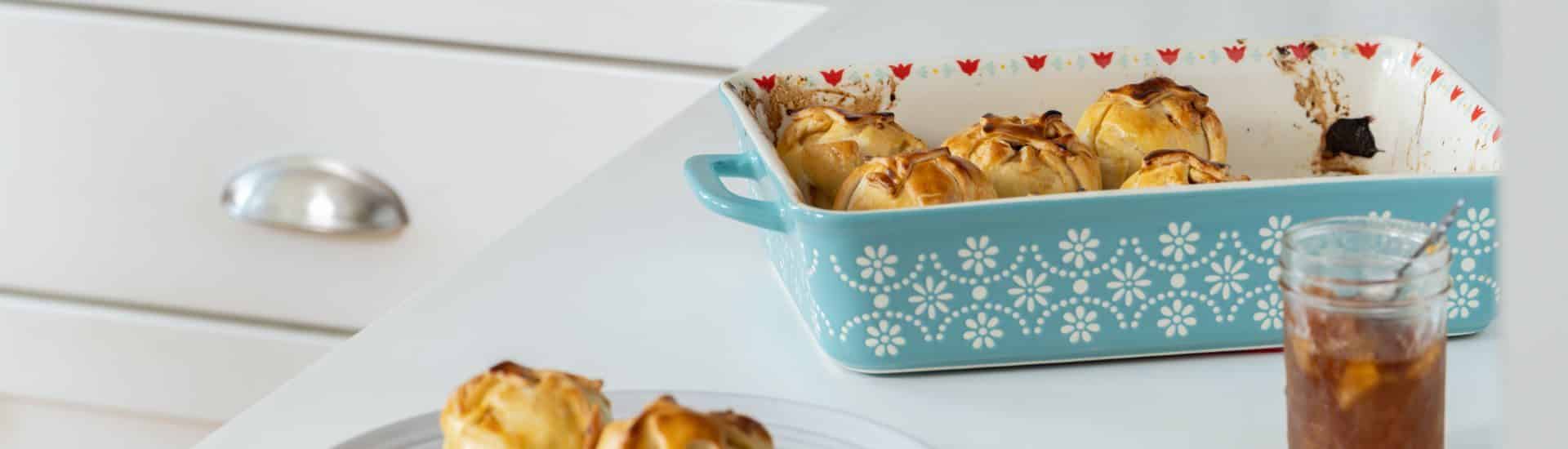 Close up view of apple dumplings in a light blue casserole dish on white counter