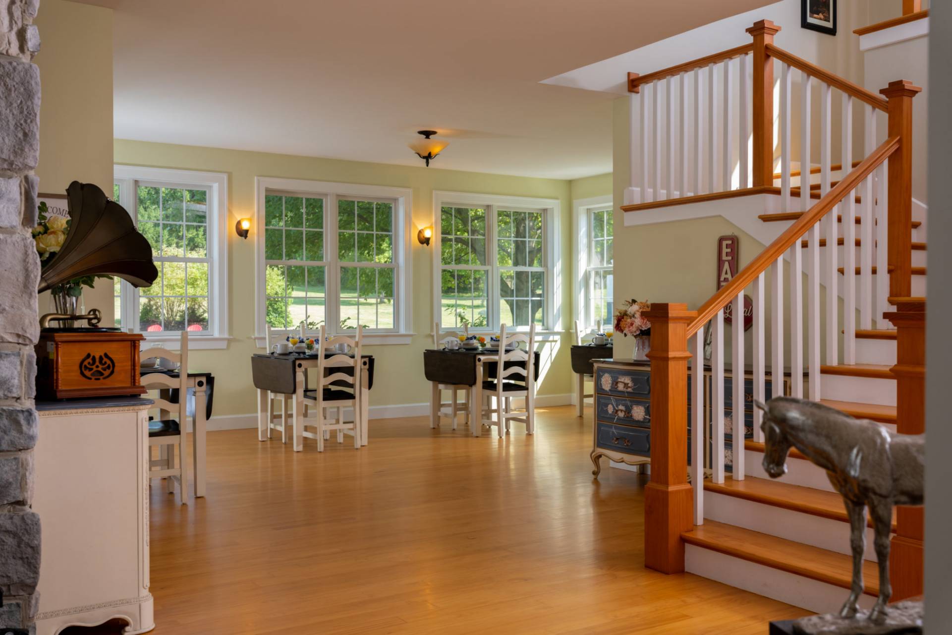 Dining area with separate white wood tables, windows to outside, hardwood floors